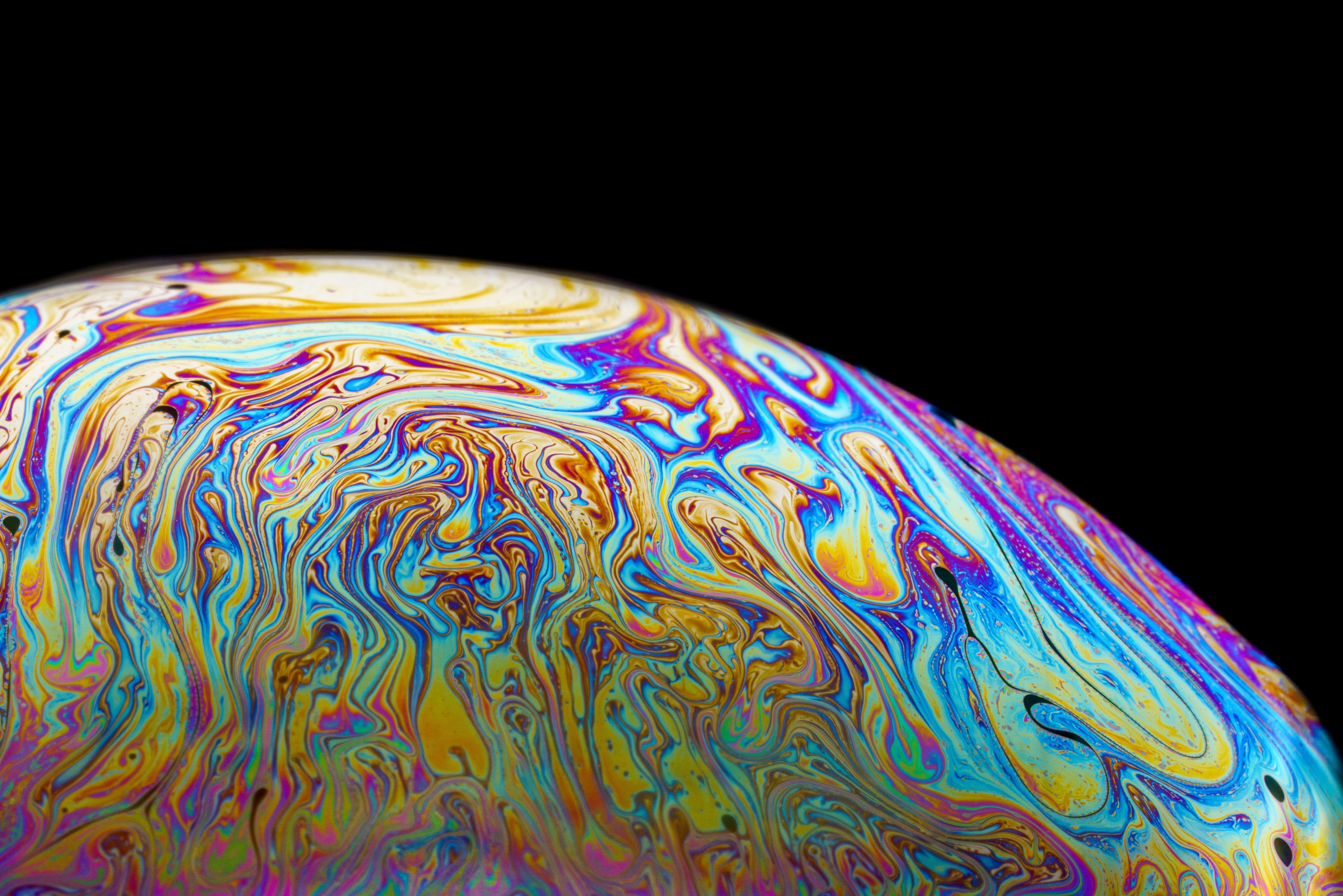 Bright swirling rainbow colors in a bubble on a black background